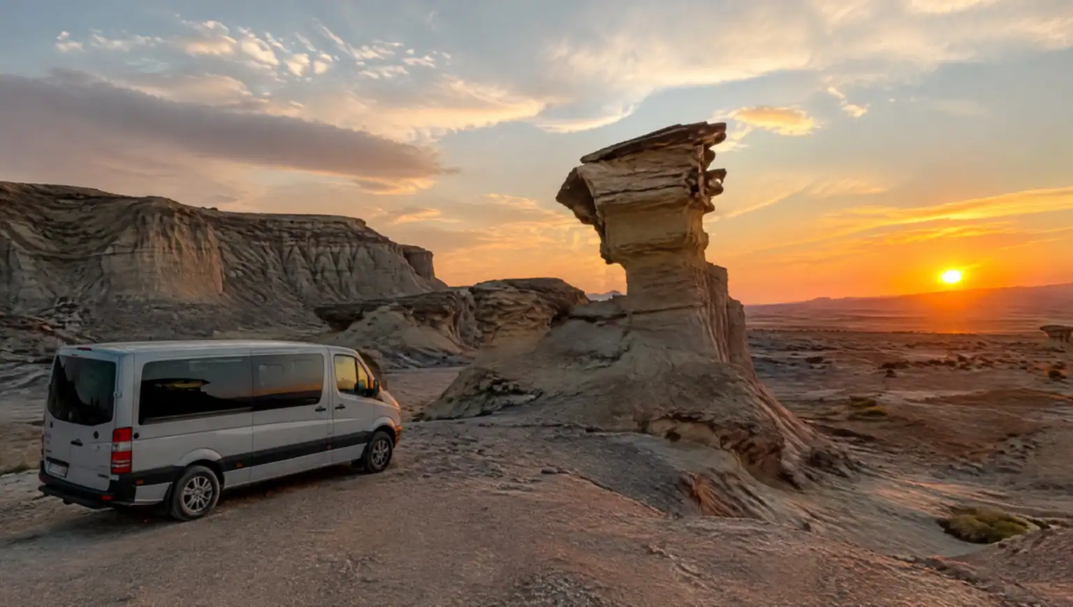 Vehículo de traslado privado estacionado frente a formaciones rocosas desérticas en el Parque Provincial Ischigualasto, Valle de la Luna, cerca de San Juan, Argentina